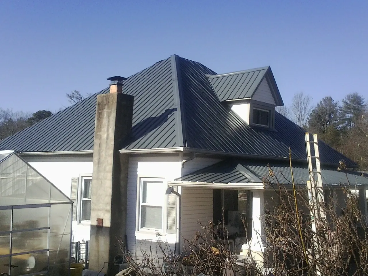 Dark blue standing seam metal roof on a white farmhouse with dormer — Slate & Tile Roof Repair by Roofing Brothers in Crandall