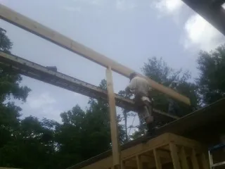 Carpenter setting a ridge beam over a new addition frame — Ice Dam Removal by Roofing Brothers in Crandall
