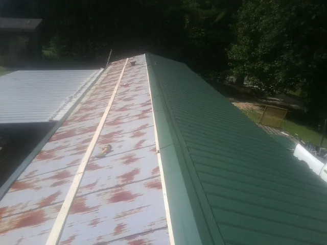 Old rusted panels beside newly installed green metal roofing — Wind Damage Roof Repair by Roofing Brothers in Crandall