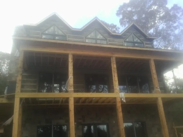 Dormers and porch framing on a large log home under construction — Roof Coating work by our crew in Crandall