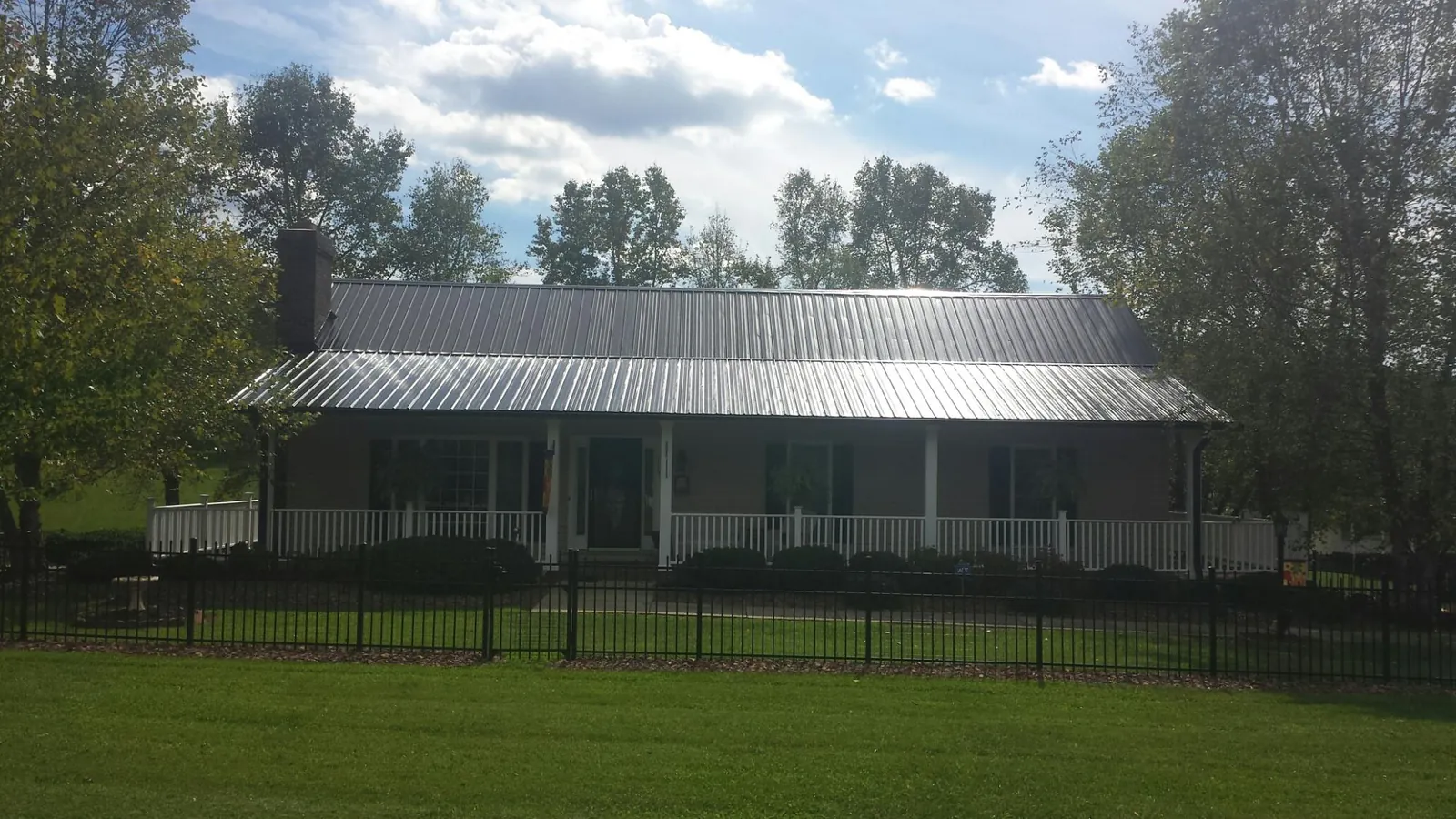 Gray metal roof on a brick ranch with a full width front porch — Gutter Guard Installation work by our crew in Crandall