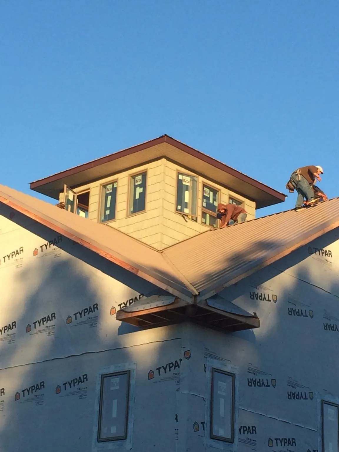 Roofers working around a rooftop cupola on a new metal roof at sunset — Roof Waterproofing in Crandall by Roofing Brothers